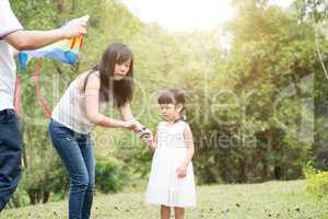 Asian family flying kite at outdoor park.