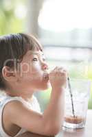 Little Asian girl drinking at cafe