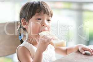 Little Asian girl eating bread