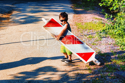 Little boy is carrying a construction site barrier