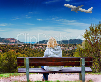 Woman on a bench, looking at a mediterranean landscape.