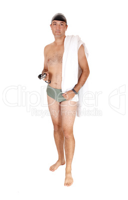 Young man in a swimsuit standing with his towel