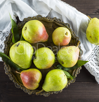 ripe green pears in an iron plate on a brown wooden table