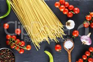 pasta spaghetti on black background, red cherry tomatoes