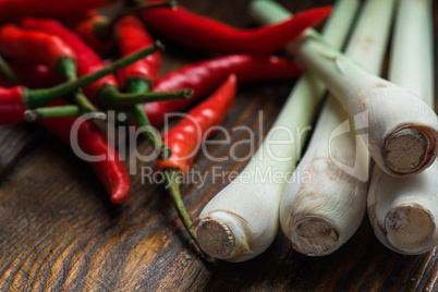 Mexican hot chili peppers with lemongrass scattered on the wooden table