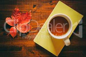 Cup of tea on a book and autumnal leaf