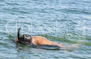 man diver with a tube floating on the surface of the water