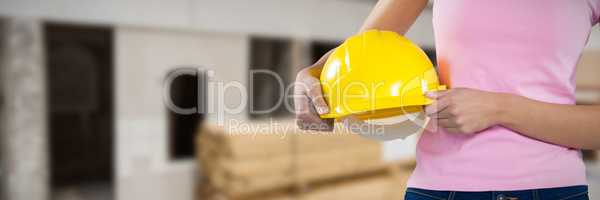 Composite image of woman holding hard hat against grey background