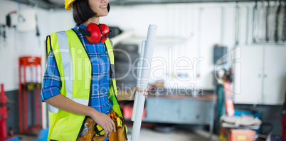 Composite image of female architect holding blueprint against grey background