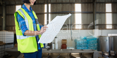 Composite image of female architect looking at blueprint against grey background