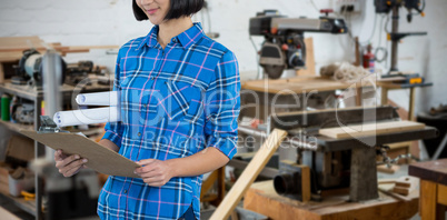 Composite image of female architect looking at clipboard against grey background