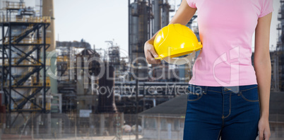 Composite image of woman holding hard hat against grey background