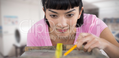 Composite image of woman measuring wooden plank with tape measure