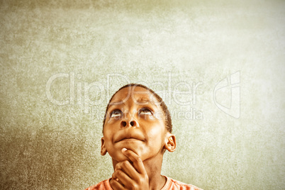 Thoughtful boy against greenboard in classroom