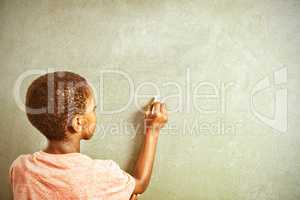Boy writing with chalk on greenboard in school