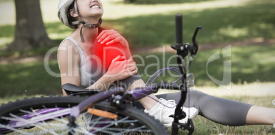 Composite image of female bicyclist with hurt leg sitting in park