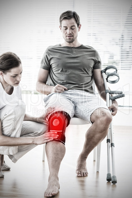 Composite image of physiotherapist examining man with crutches