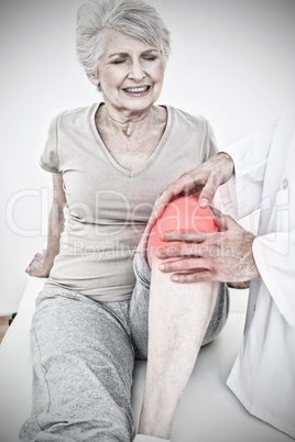 Composite image of displeased senior woman getting her knee examined