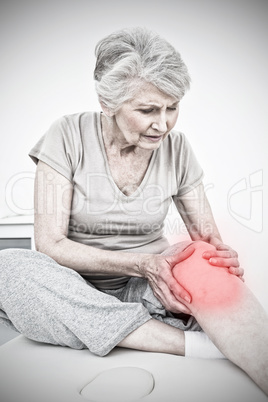 Composite image of senior woman with her hands on a painful knee