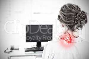 Composite image of rear view of a businesswoman with neck pain in office