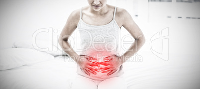 Composite image of casual woman with stomach pain sitting in bed