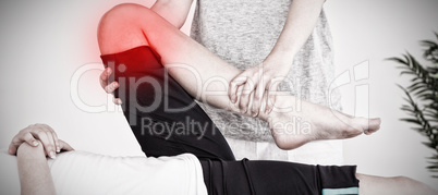 Composite image of masseuse stretching the leg of a youn woman