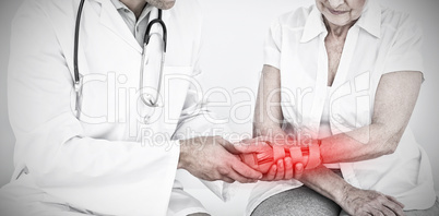 Composite image of male physiotherapist examining a senior womans wrist