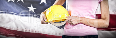 Composite image of woman holding hard hat against grey background