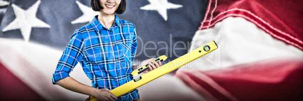 Composite image of female architect holding measuring equipment against grey background