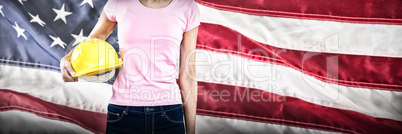 Composite image of woman holding hard hat against grey background