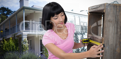 Composite image of woman measuring furniture with tape measure