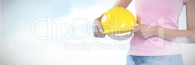 Composite image of woman holding hard hat against grey background