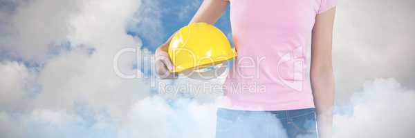 Composite image of woman holding hard hat against grey background