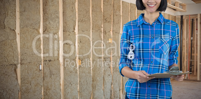 Composite image of female architect holding clipboard and blueprint against grey background