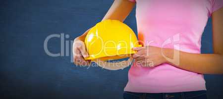 Composite image of woman holding hard hat against grey background