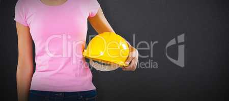 Composite image of woman holding hard hat against grey background