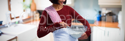 Composite image of female chef mixing flour in bowl with whisk