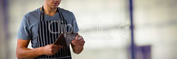 Composite image of male waiter using digital tablet