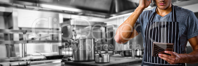 Composite image of waiter talking on mobile phone while holding digital tablet