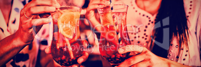 Mid-section of two young women having cocktail drinks