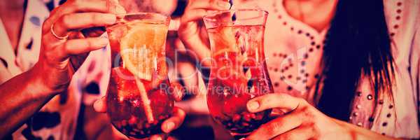 Mid-section of two young women having cocktail drinks