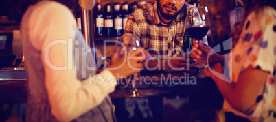 Young women interacting with bartender at counter