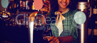 Portrait of waitress using beer tap at counter