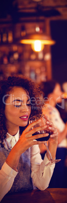 Young woman having red wine in pub