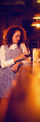 Thoughtful woman having red wine at counter