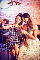 Young women taking a selfie while having cocktail drinks