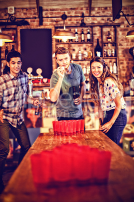 Group of happy friends playing beer pong game