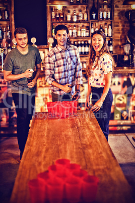 Group of happy friends playing beer pong game