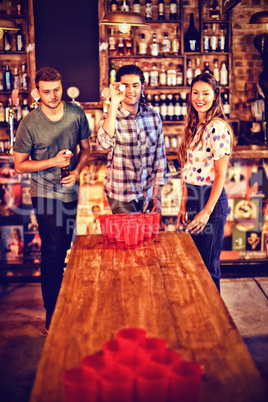 Group of happy friends playing beer pong game