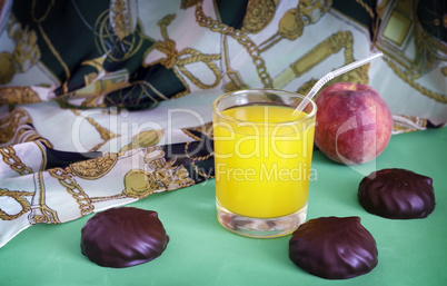 Still life: fresh orange juice, candy, Apple.